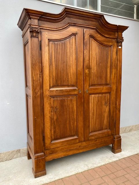 Walnut wardrobe with 2 doors, pilasters on uprights with carved capitals.