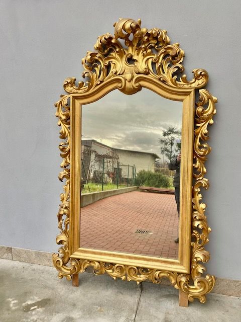 Important Cartoccio Mirror in carved wood and gilded with leaf.